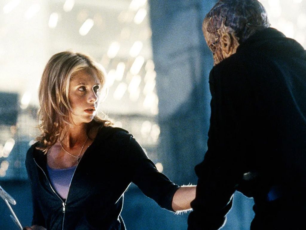 Buffy from the television series "Buffy the Vampire Slayer" holds a weapon in her hand and lunges at a monster.