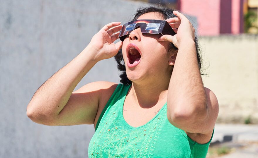 Woman looking at an eclipse while wearing protective glasses with her mouth open