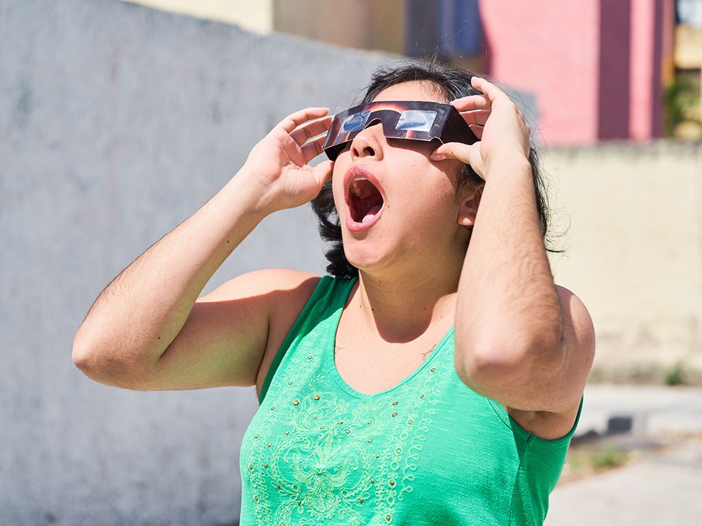 Woman looking at an eclipse while wearing protective glasses with her mouth open