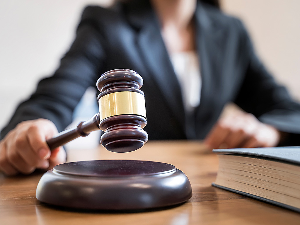 Woman judge hand holding gavel to bang on sounding block in the court room.
