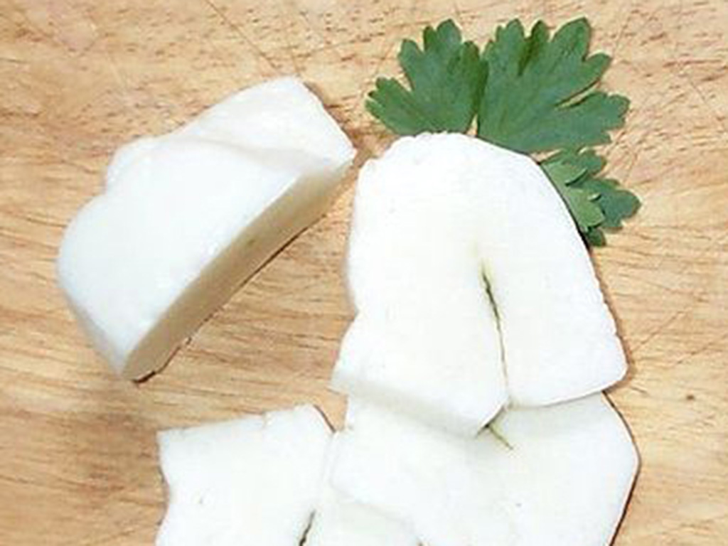Fresh sliced Halloumi cheese. The strip in the middle contains whole leaves of mint.