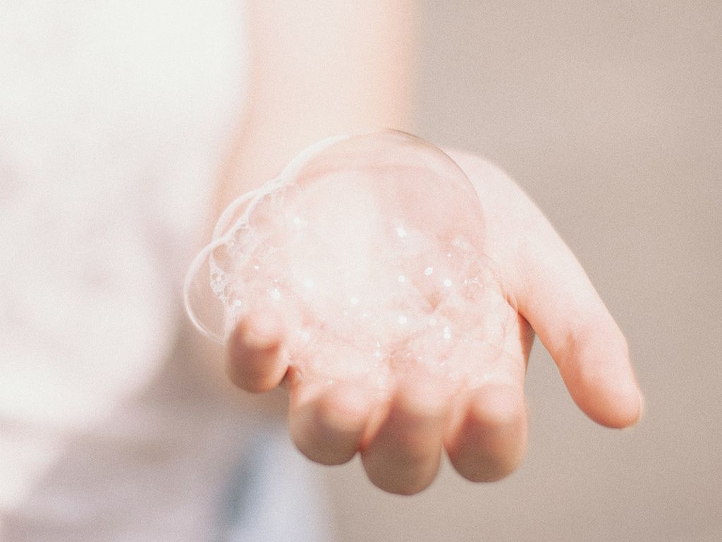 A person holding soap bubbles in their hand