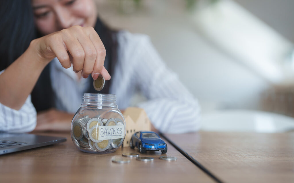 Woman putting coins in a jar marked "savings"